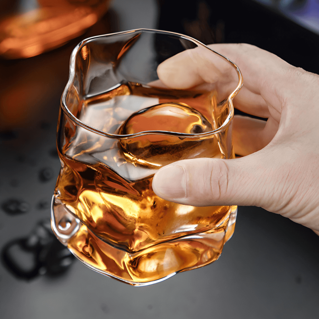 Hoshi crystal whisky glass held by hand, amber whisky inside with faceted walls