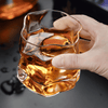 Hoshi crystal whisky glass held by hand, amber whisky inside with faceted walls