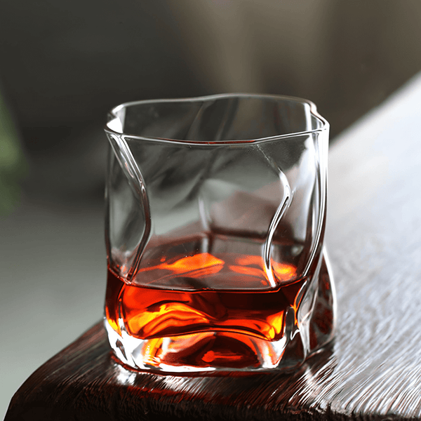 Hoshi Japanese crystal whisky glass with amber whisky on dark wood and textured cloth