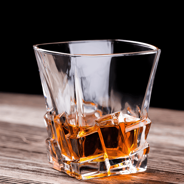 Clear faceted whisky glass with amber liquid pooling in square base