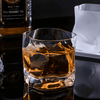 Crystal whiskey tumbler with amber drink and bright glass reflections