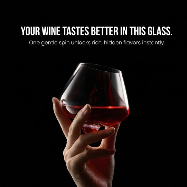 Hand holding crystal wine glass with red wine above a dark background
