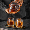 Football-shaped whiskey decanter being held above two amber tumblers