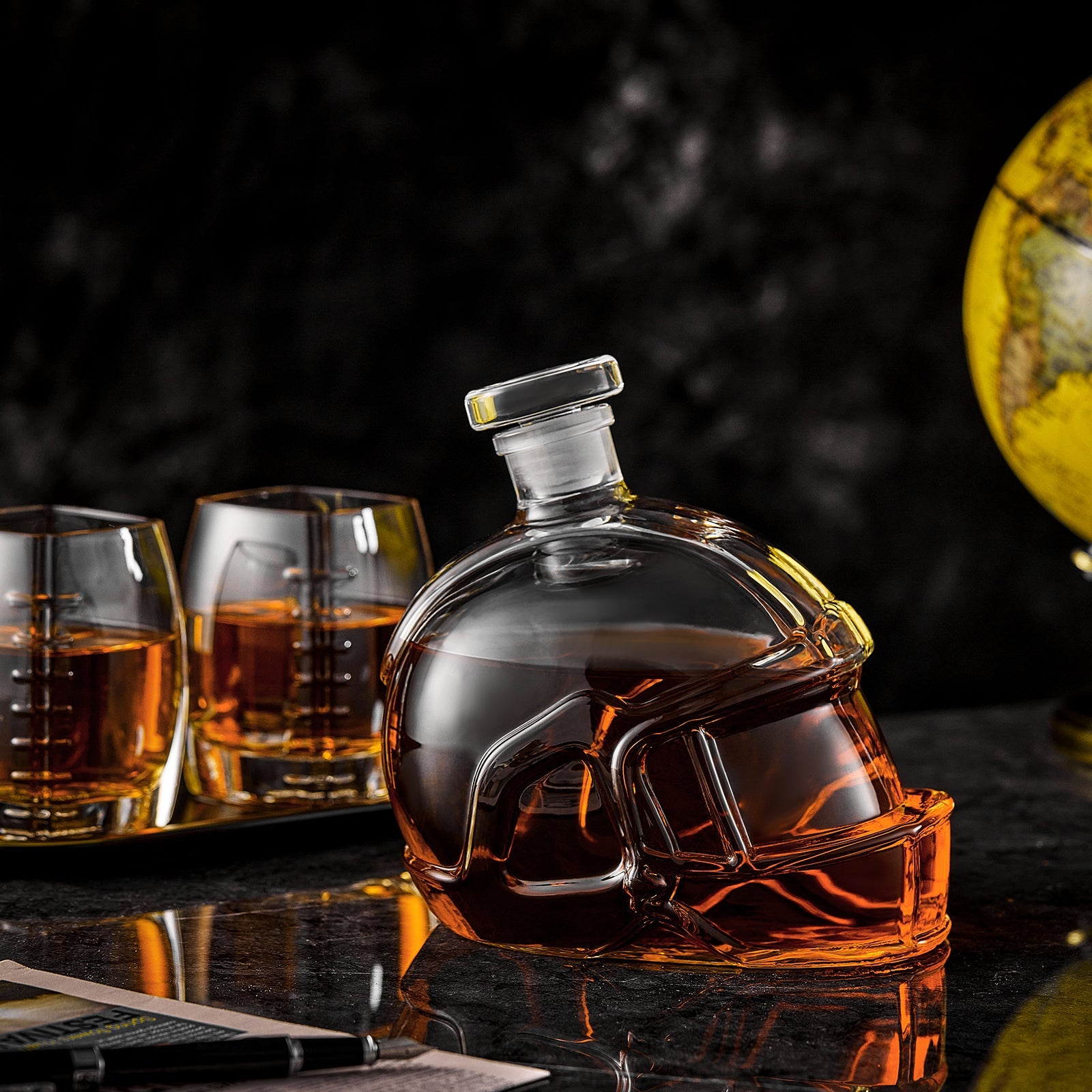 Close-up football-shaped whiskey decanter with amber tumblers