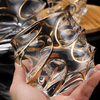 Handheld view of clear crystal whisky glass with raised gold line swirl pattern