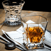 Faceted whisky glass with amber liquid, cut-step pattern on the base