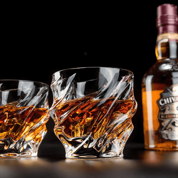 Crystal whisky glass with faceted wave pattern and thick rounded rim, amber reflections