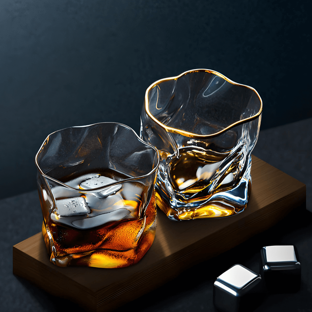 Set of two gold-rim whisky glasses on a wooden tray with amber liquid