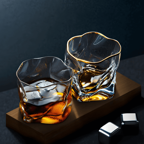 Set of two gold-rim whisky glasses on a wooden tray with amber liquid