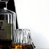 Japanese crystal whisky glass with fluted sides, amber whisky pooled at the base