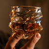 Japanese crystal whisky glass with gold line swirl pattern, held up