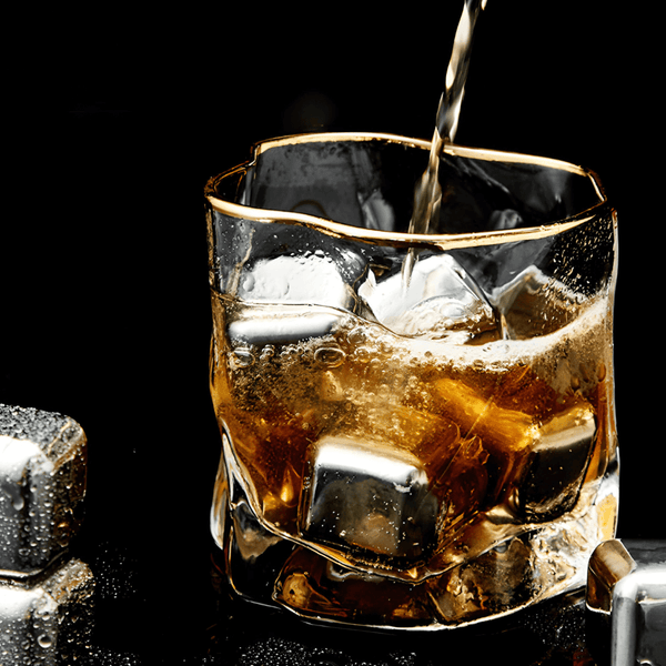 Gold Hoshi whisky glass with gold rim, clear crystal filled with amber drink and ice