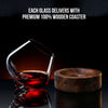 Rotating crystal wine glass with red wine and round wooden coaster