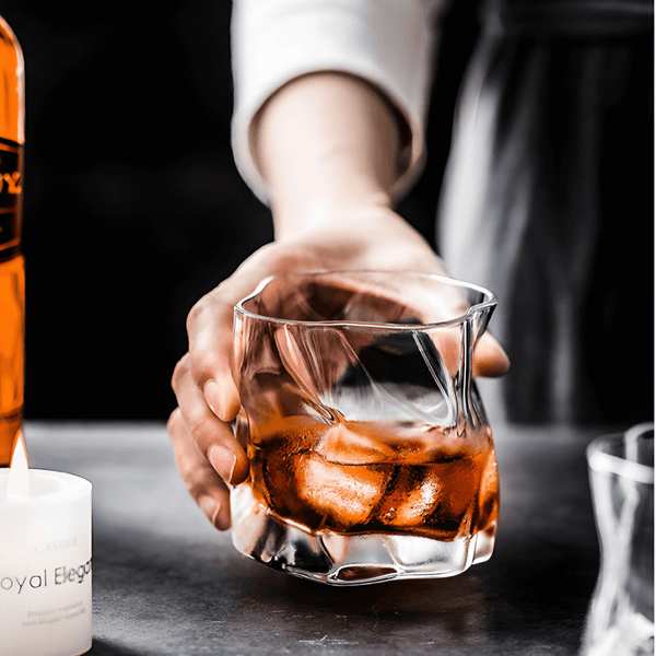 Hand pouring amber whisky into a faceted crystal whiskey glass