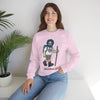 Light pink crewneck sweatshirt with hiker graphic, model seated