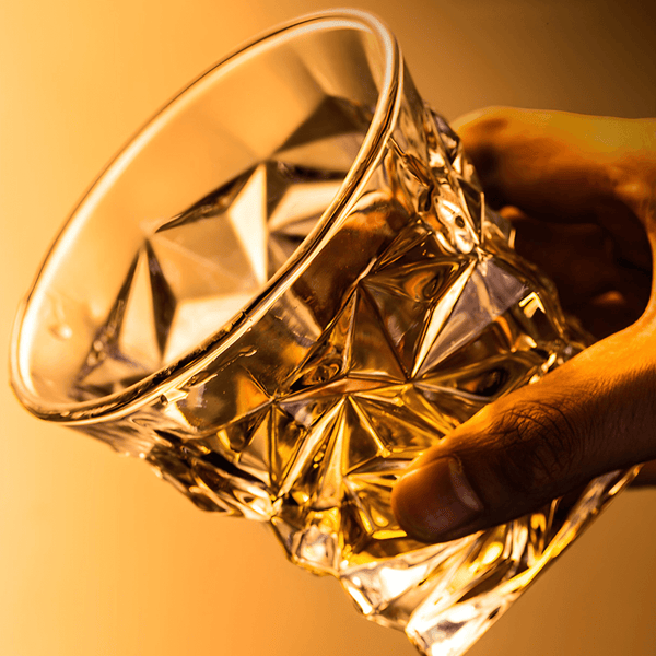 Hand holding a golden faceted Japanese crystal whisky tumbler