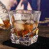 Faceted whisky glass with amber drink and ice cubes, square base