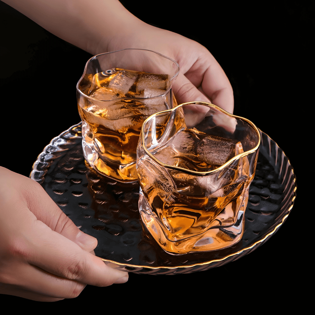 Gold Hoshi whisky glass set, gold-rim amber drinks held in hands with ice-filled glass