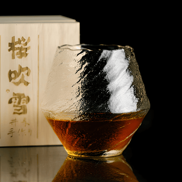 Textured crystal whisky glass with amber liquid inside and faceted irregular shape