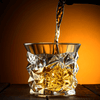 Crystal whisky tumbler with geometric facets as amber drink pours in