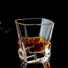 Faceted whisky glass with amber liquid, reflective angular walls and base