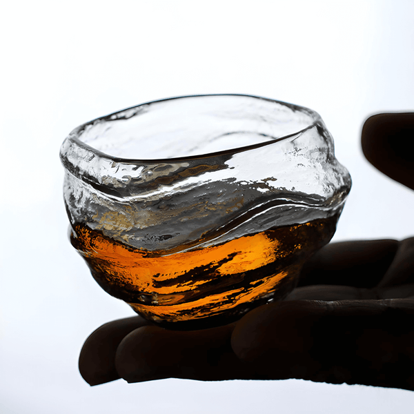 Crystal whisky glass with faceted rim and amber liquid at center.