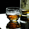 Crystal whisky glass with amber liquid, textured wavy pattern around bowl.
