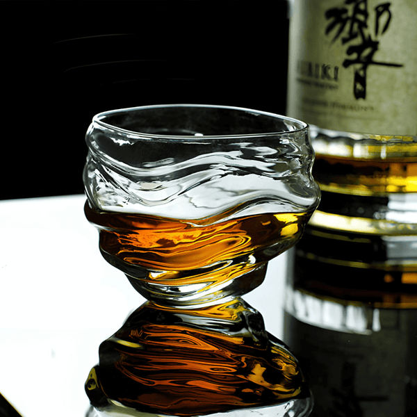 Crystal whisky glass with amber liquid, textured wavy pattern around bowl.