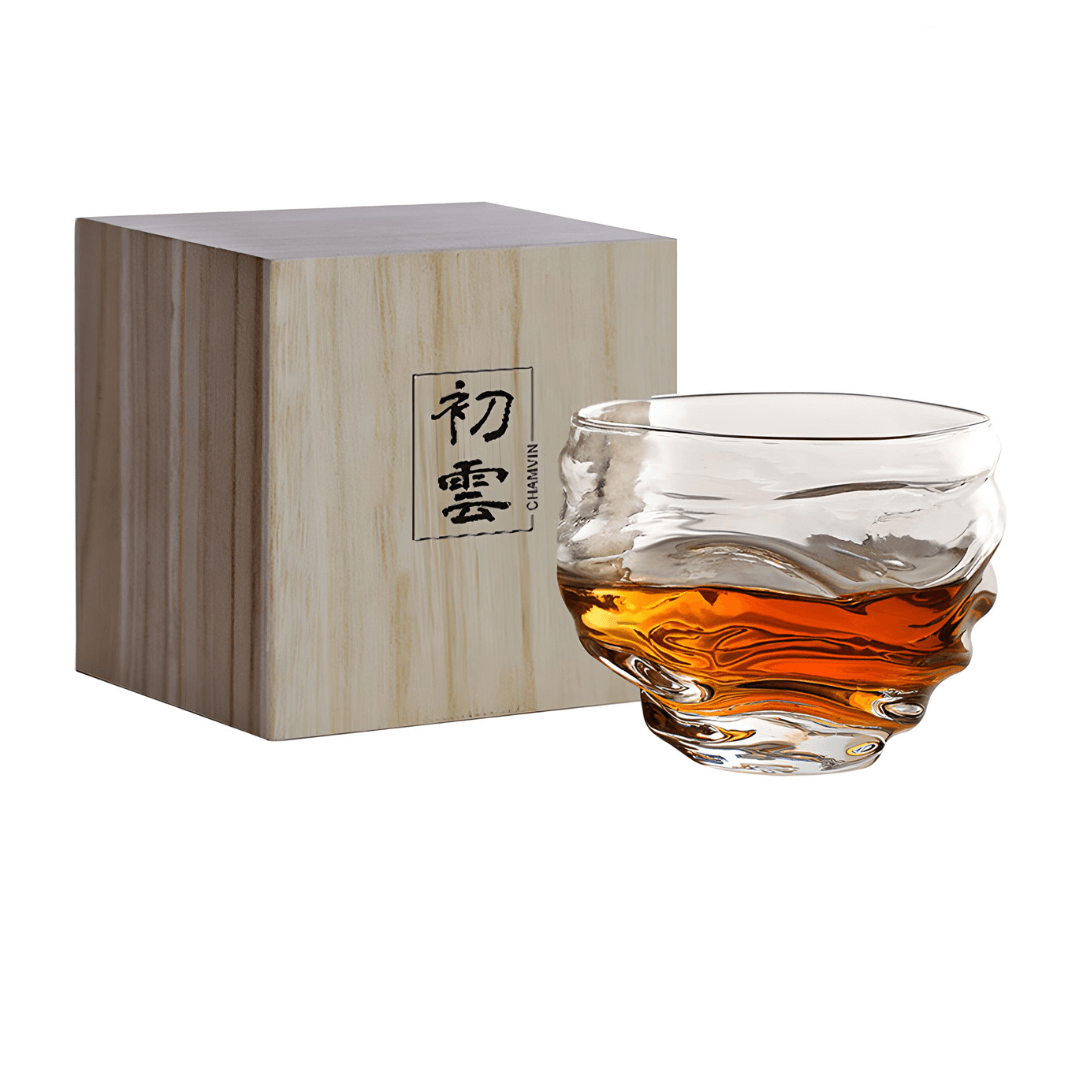 Crystal whisky glass with amber whisky, beside wooden gift box