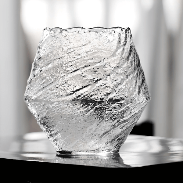 Textured crystal whisky glass, clear finish, faceted irregular shape on tabletop
