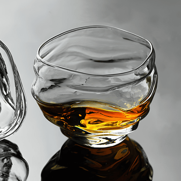 Crystal whisky glass side view with amber whisky, faceted reflections
