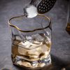 Gold Hoshi whisky glass with gold rim, ice cubes dropping into clear amber crystal