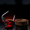 Crystal wine glass with red wine beside wooden coaster