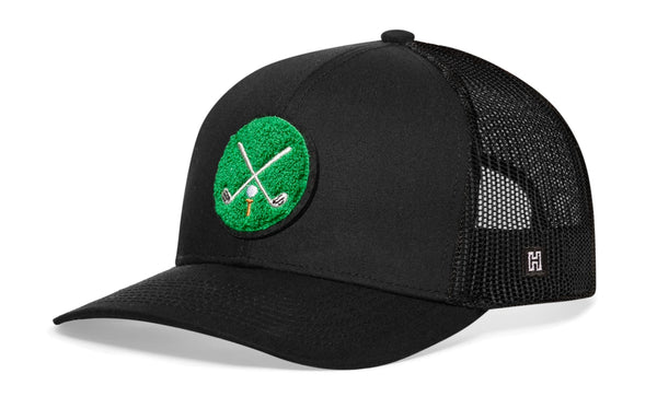 Black trucker snapback hat with green crossed clubs patch and mesh side panels.