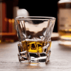Faceted whisky glass with amber liquid, thick crystal base and side facets