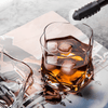 Whiskey glass filled with amber liquor and ice cubes on a tray