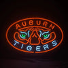 Neon oval tiger sign with Auburn text, orange border and blue-green eye lights