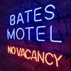 Neon sign reading BATES MOTEL (blue) and NO VACANCY (red) on wall mount.