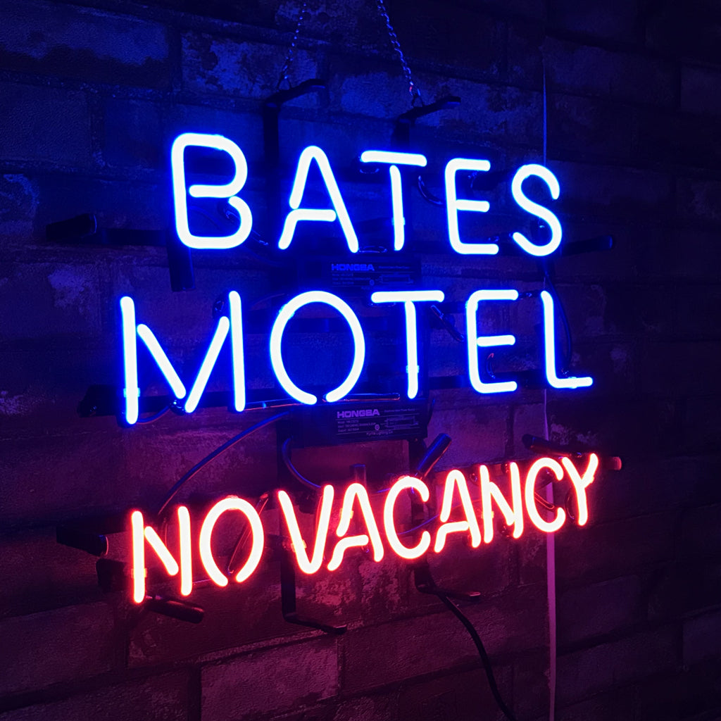 Neon sign reading BATES MOTEL (blue) and NO VACANCY (red), centered.