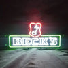Neon beer sign with green and pink outline, BECK'S wordmark and beer glass icon