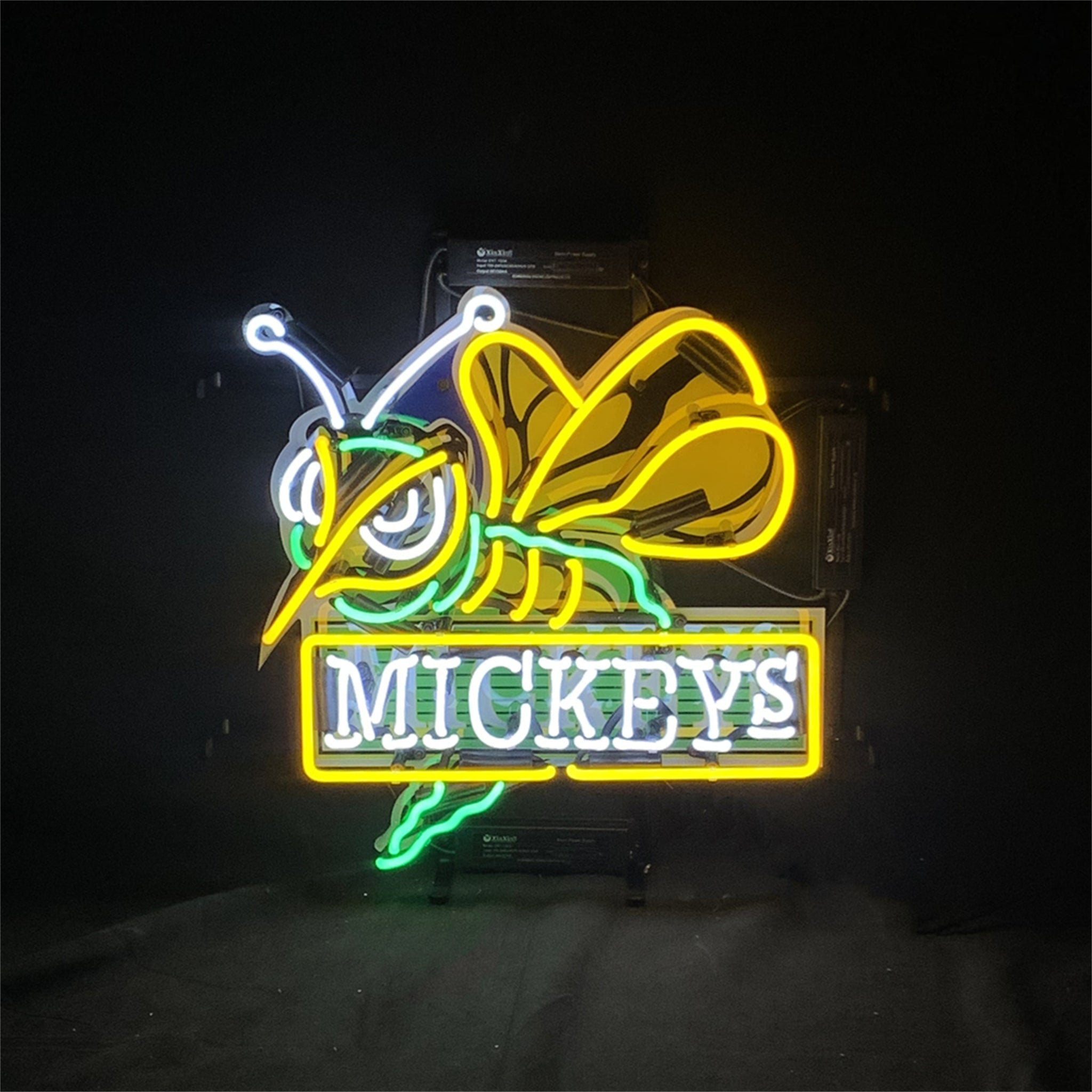 Neon sign with bee-and-Mickey design, glowing yellow, blue, and green, 'MICKEY'S'.
