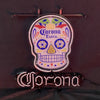 Neon skull sign mounted on metal bars, Corona Extra text glowing