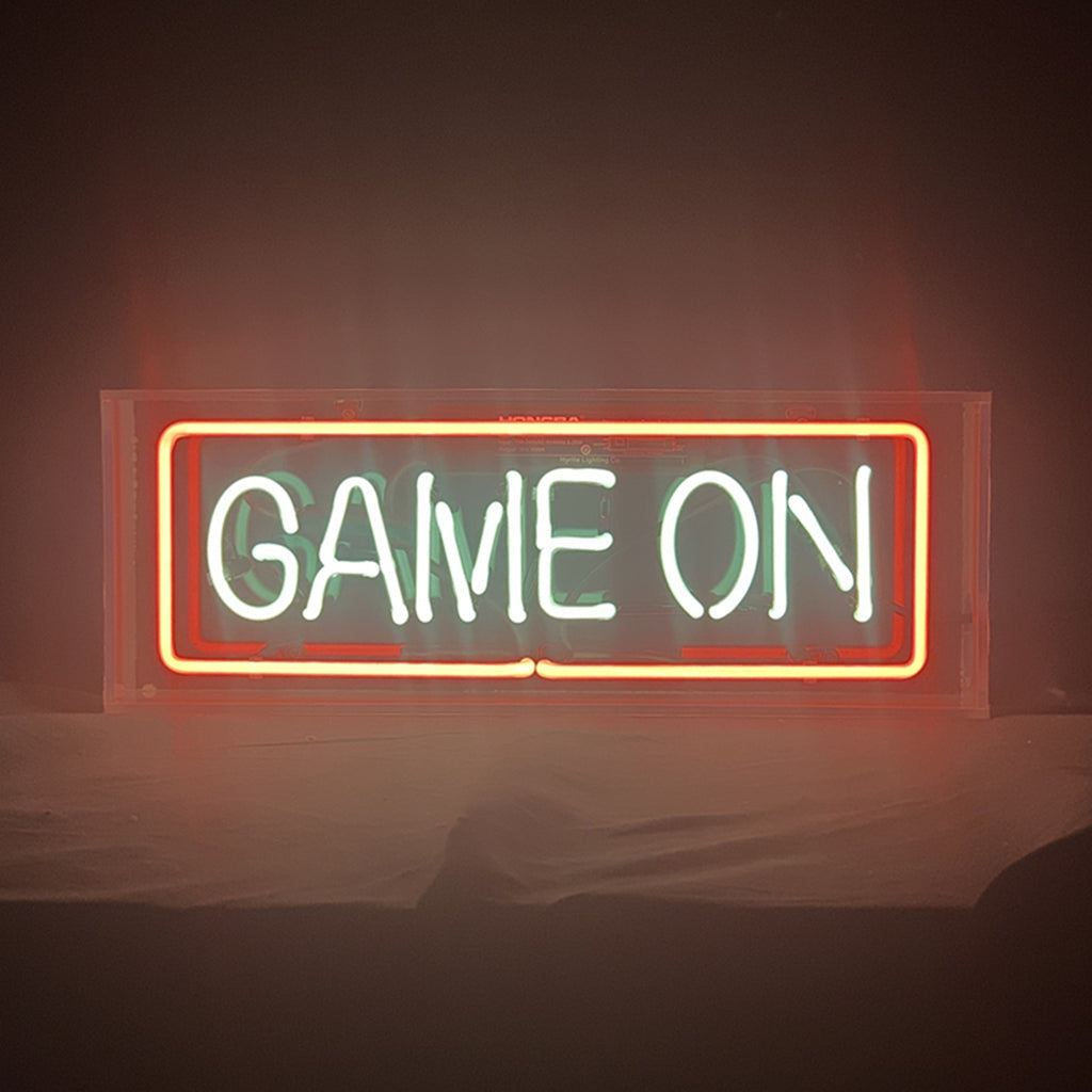 Neon sign reading “GAME ON” in an orange-red framed glow with green text