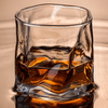 Faceted crystal whiskey glass with amber drink and ice cubes