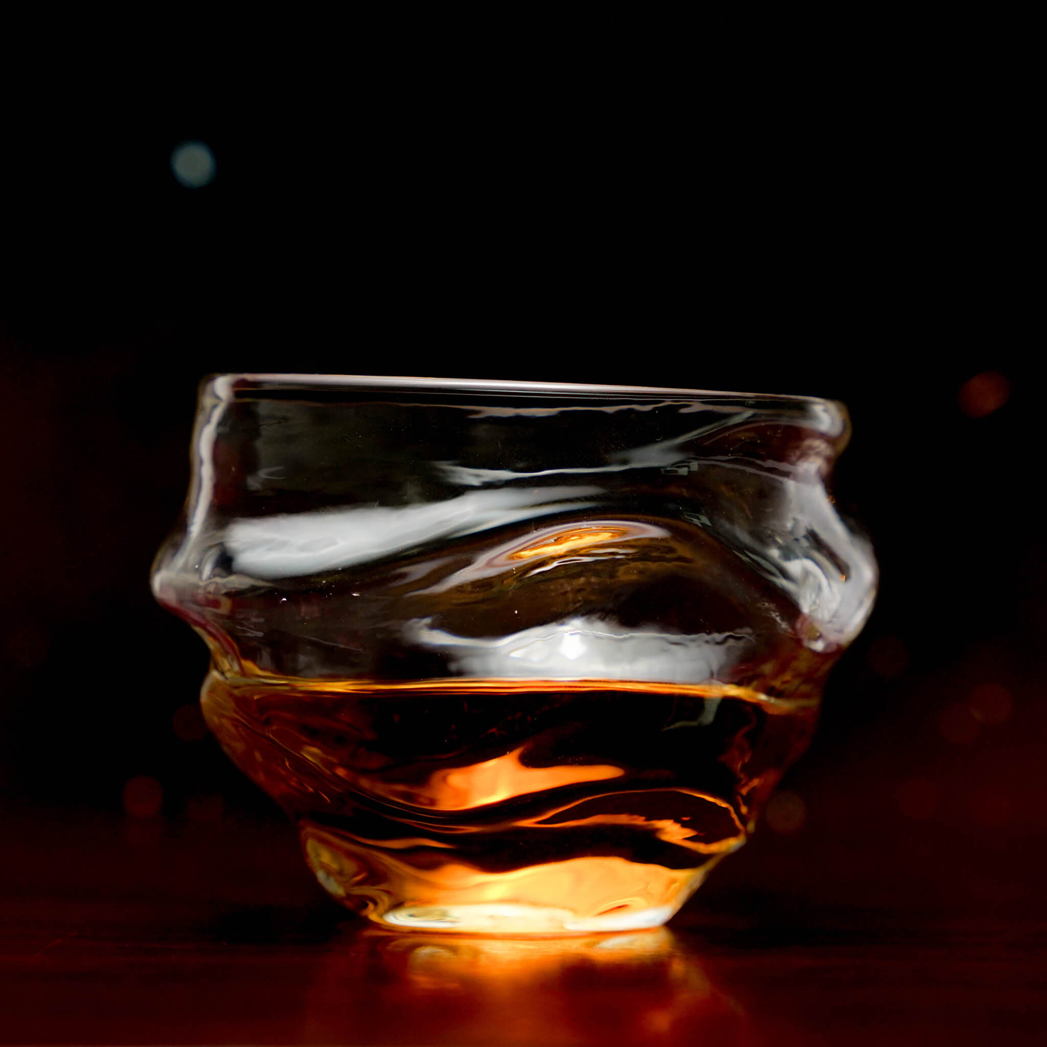 Crystal whisky glass with amber whisky, wide bowl and fluted base