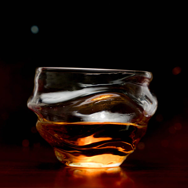 Crystal whisky glass with amber whisky, wide bowl and fluted base