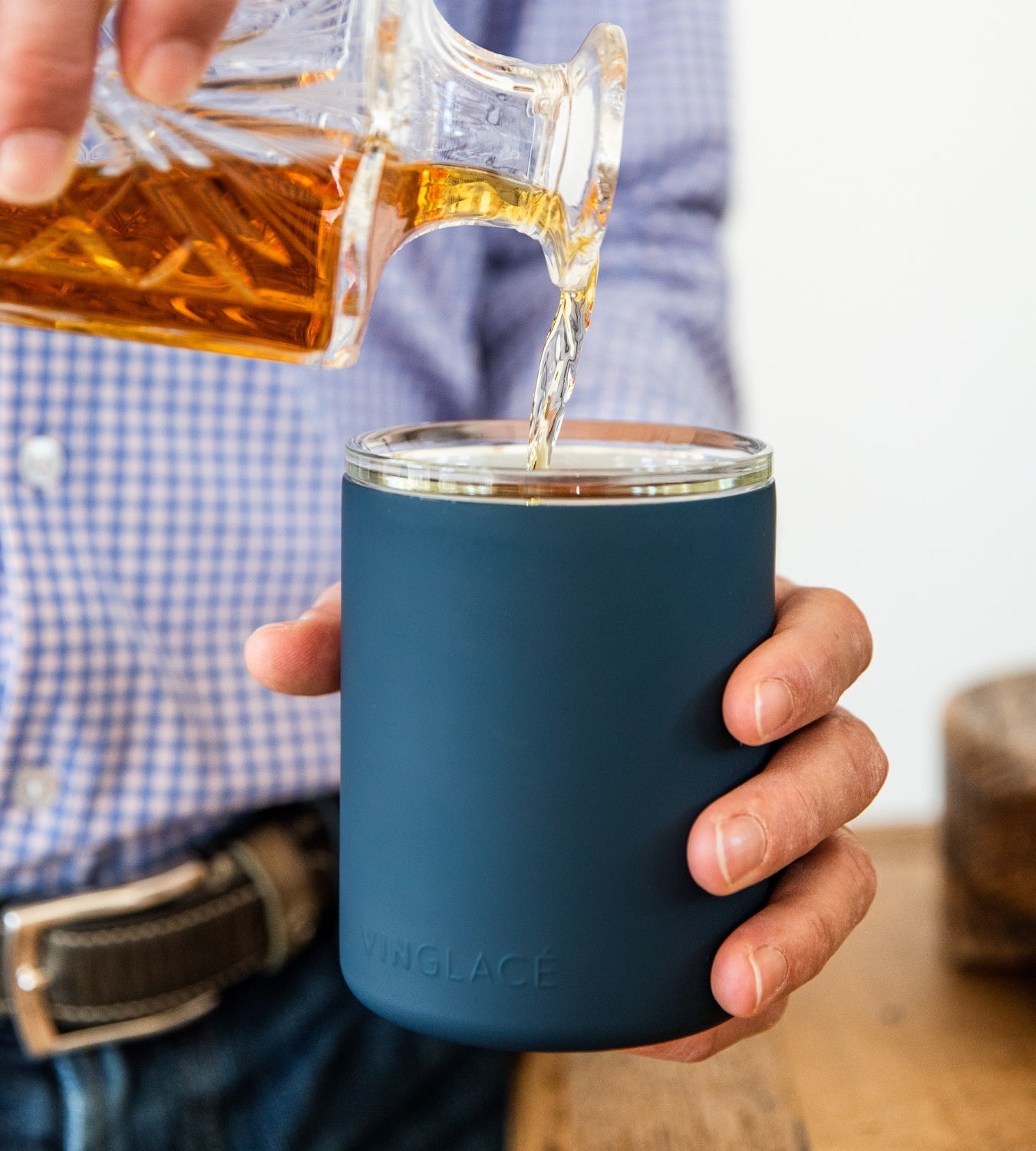 Navy glass-lined lowball whiskey tumbler with whiskey being poured into the cup