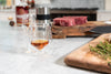 Pair of clear double-walled glass tumblers with amber drinks on table