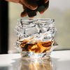 Crystal tumbler whisky glass with faceted sides and amber liquid, held by hand
