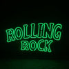 Green neon sign reading “ROLLING ROCK” centered on dark background